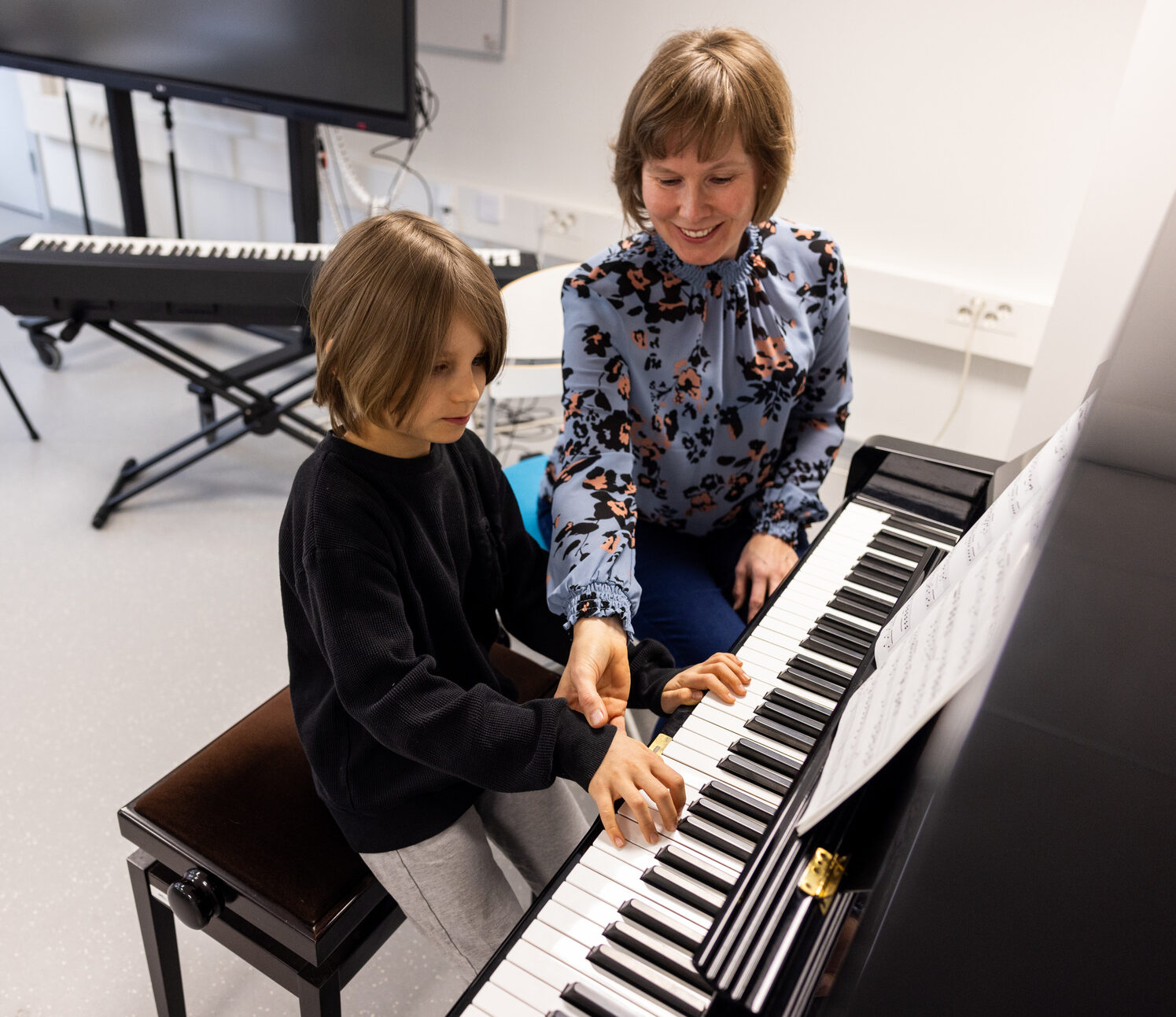Aikuinen opettaa lasta soittamaan pianoa